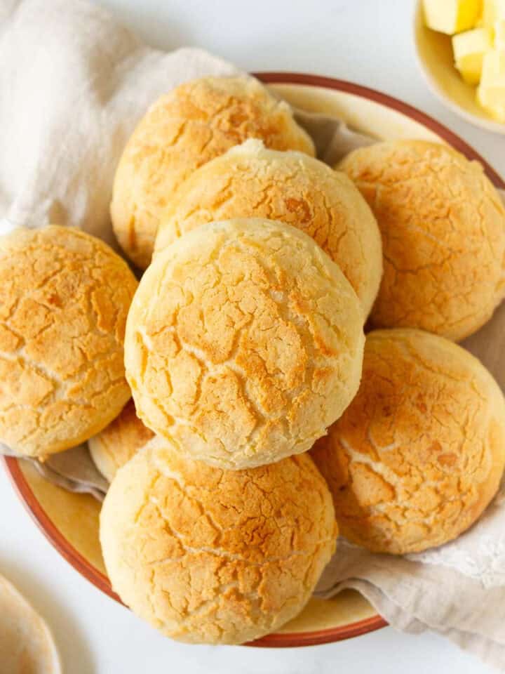 Bread rolls in a napkin lined bowl with butter on the side.