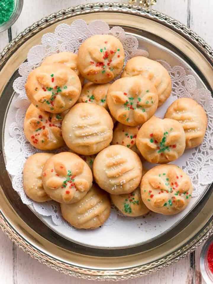 Cookies with sprinkles on a doily-lined platter.