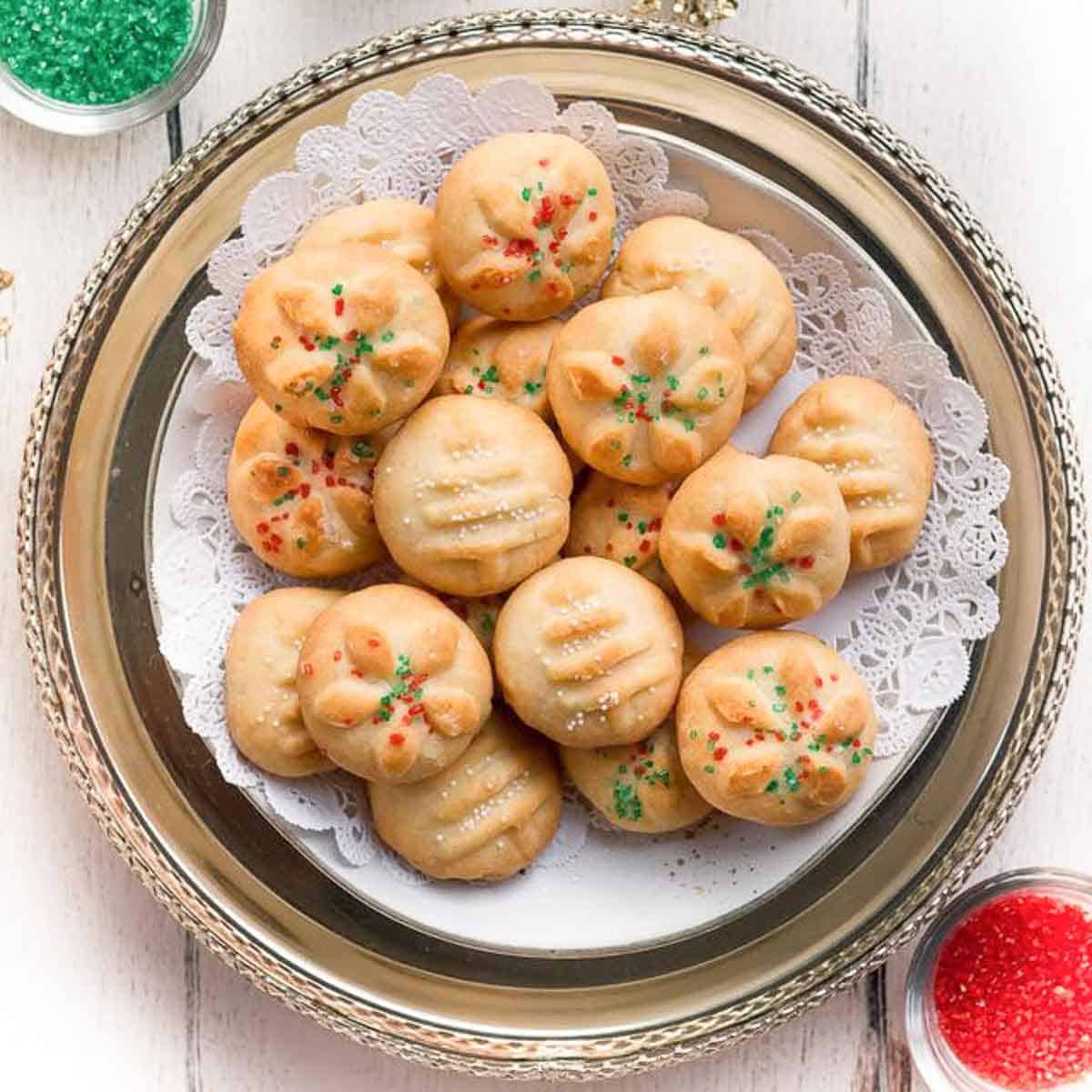 Cookies with sprinkles on a doily-lined platter.
