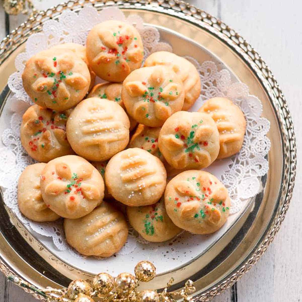 Cookies with sprinkles on a paper doily on a serving platter.