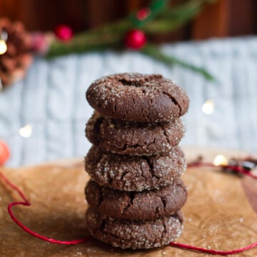 Five Chocolate ginger cookies stacked up on parchment paper with a red string.