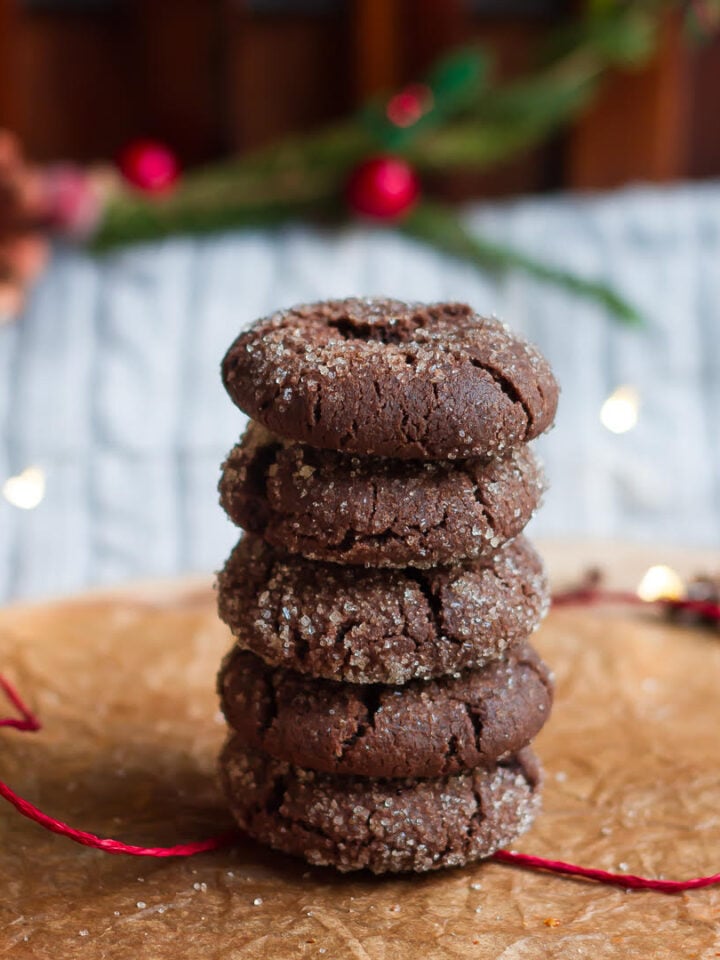 Five Chocolate ginger cookies stacked up on parchment paper with a red string.