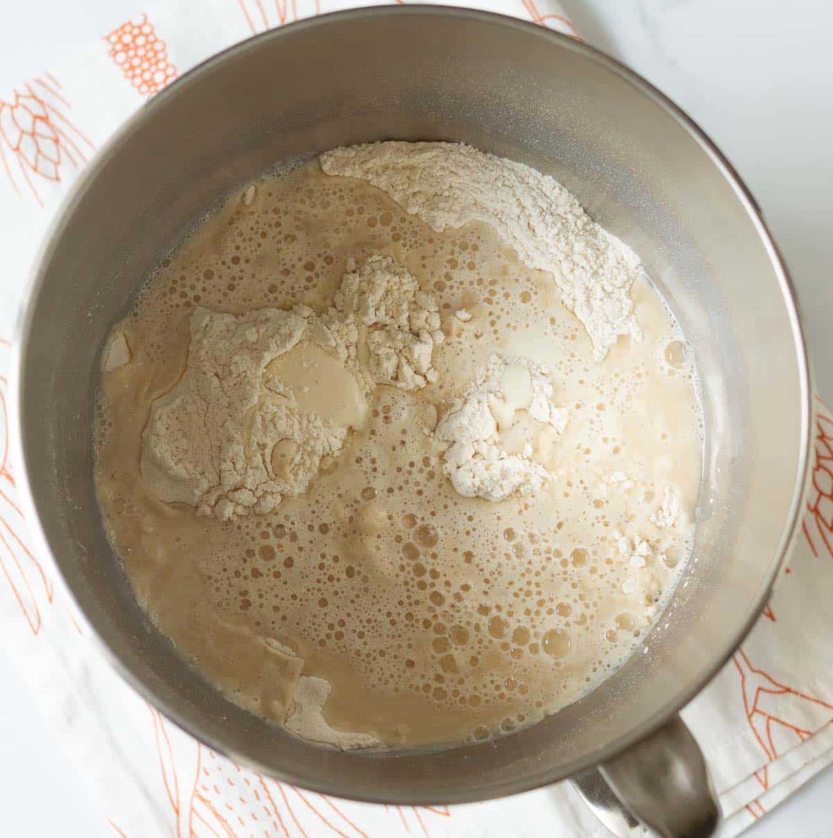 Flour, yeast mixture, and sourdough discard in a mixer stand bowl.