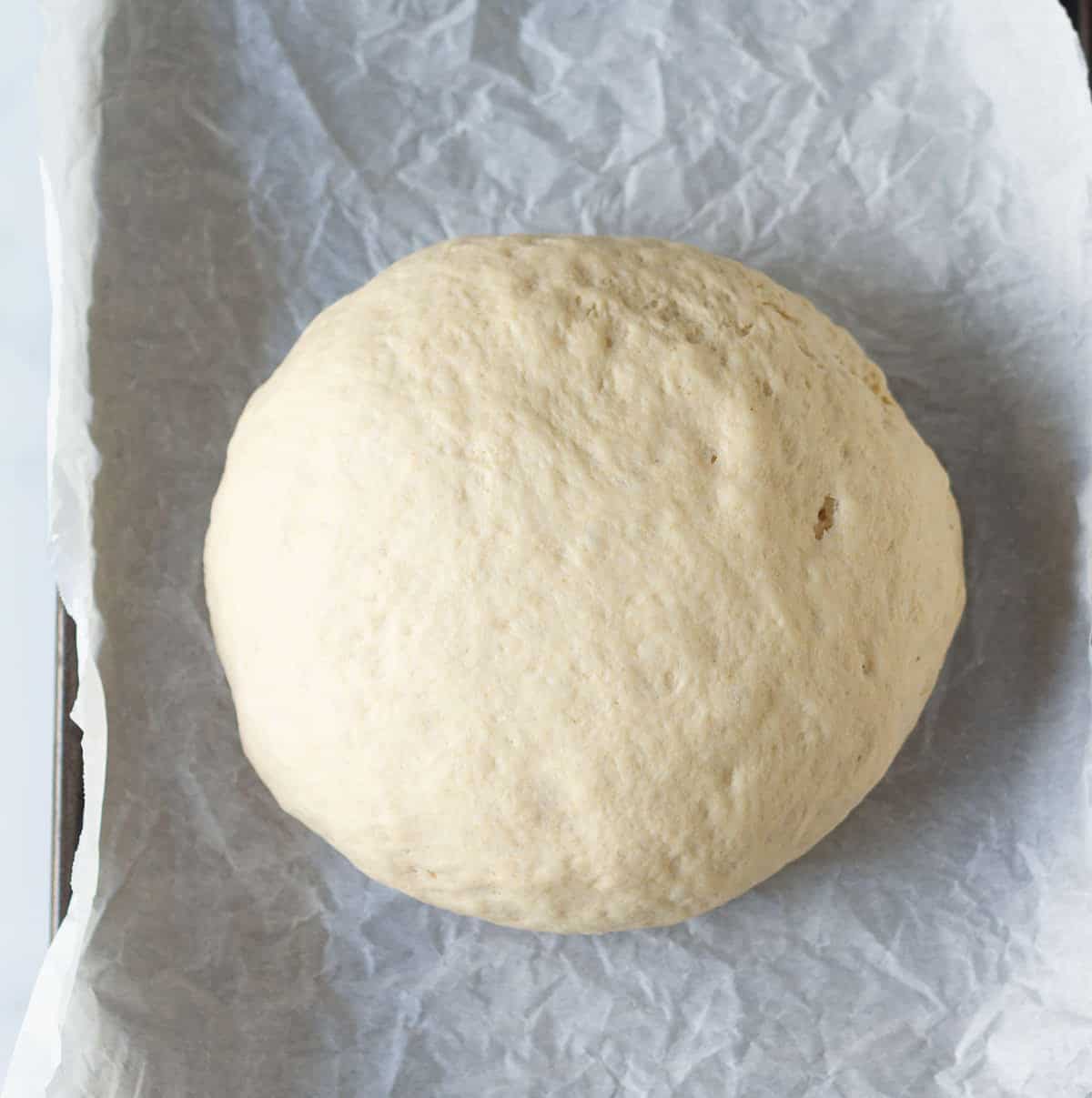 Proofed dough ball on parchment paper.