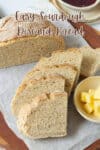 Half a loaf of bread with some slices of with butter in a small dish on the side.