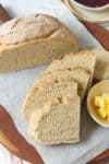 Half a loaf of bread with some sliced bread with butter in a dish.
