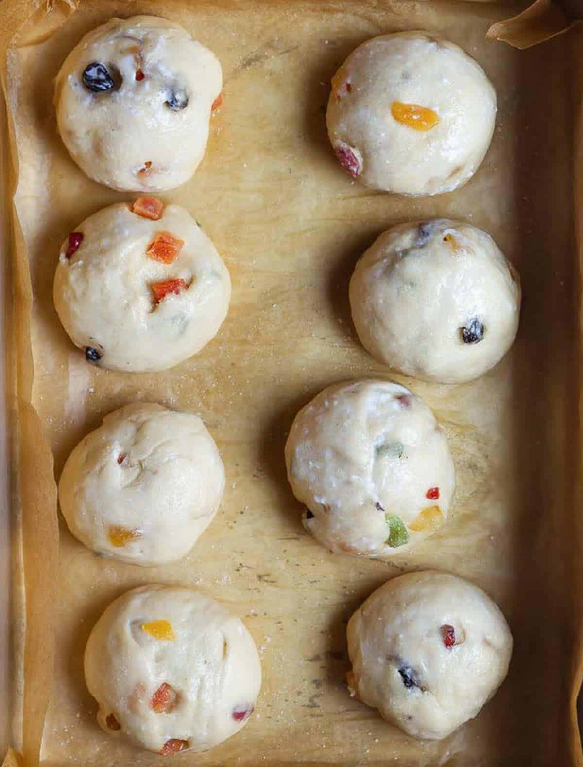 Proofed buns on parchment paper lined tray.