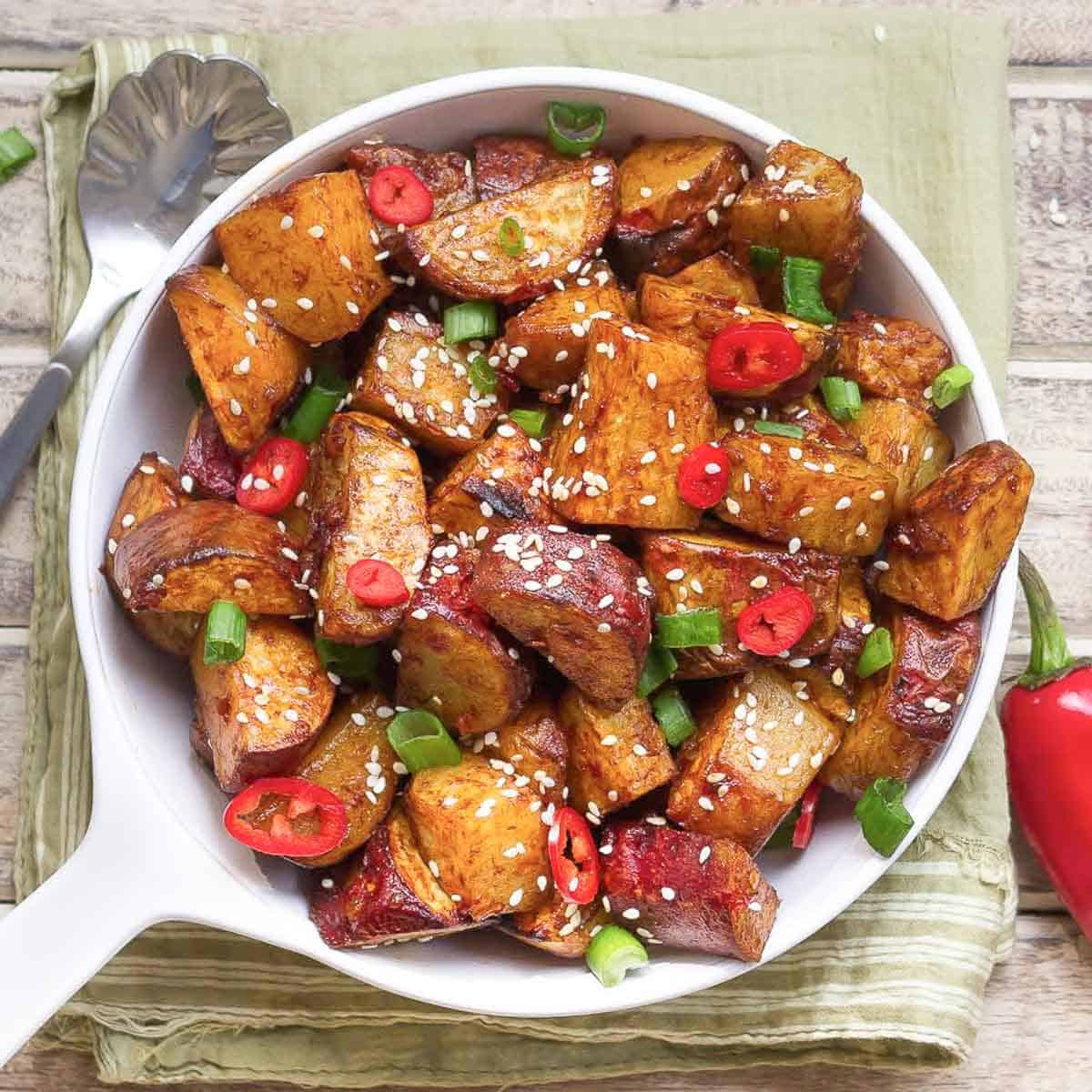 sticky chili sweet potatoes with red chili and green onions garnish.