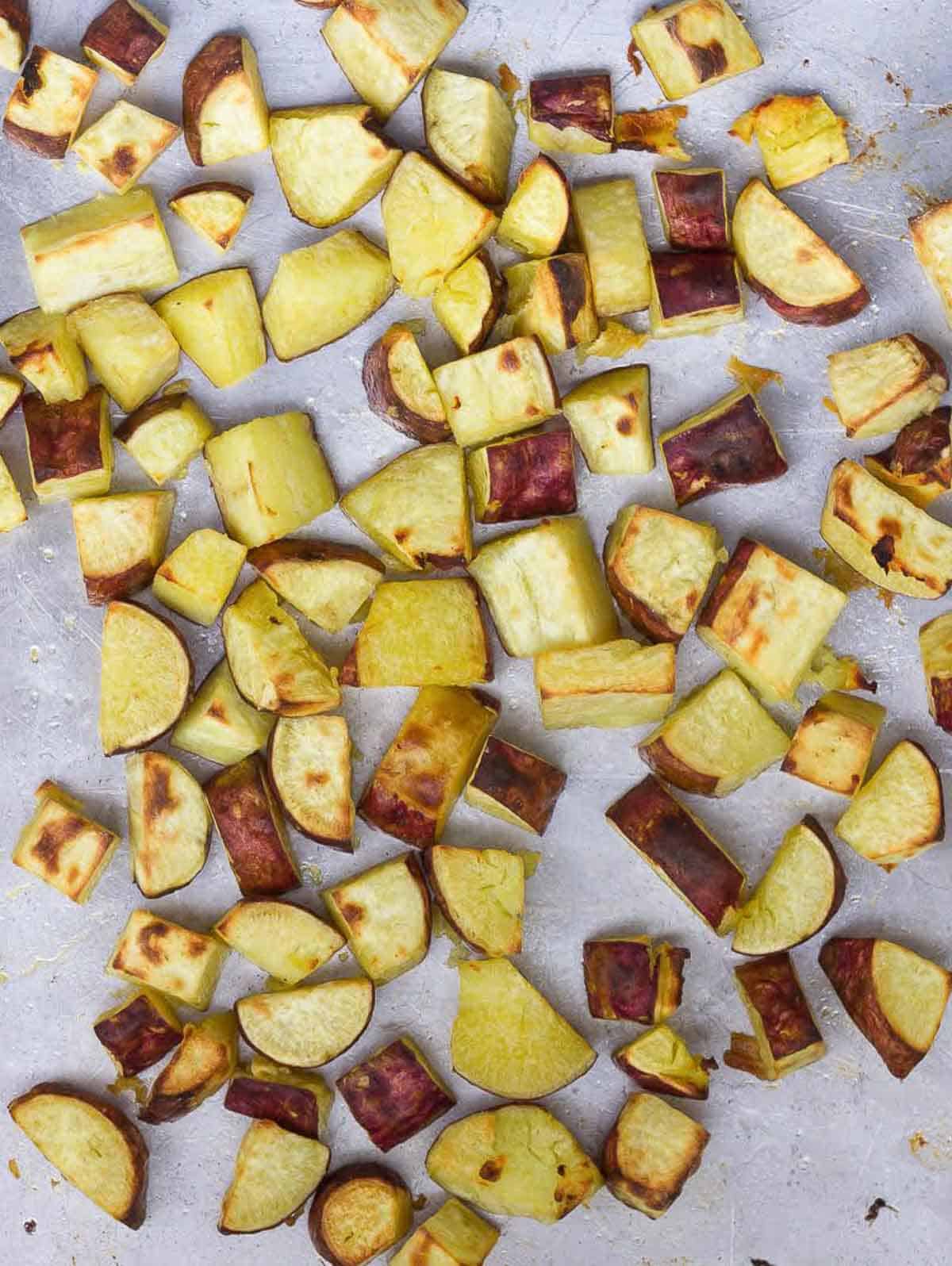 Roasted cubed sweet potatoes on a baking tray.