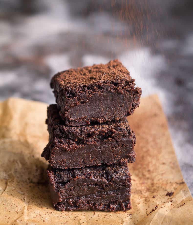 A stack of 3 brownie pieces on parchment paper.