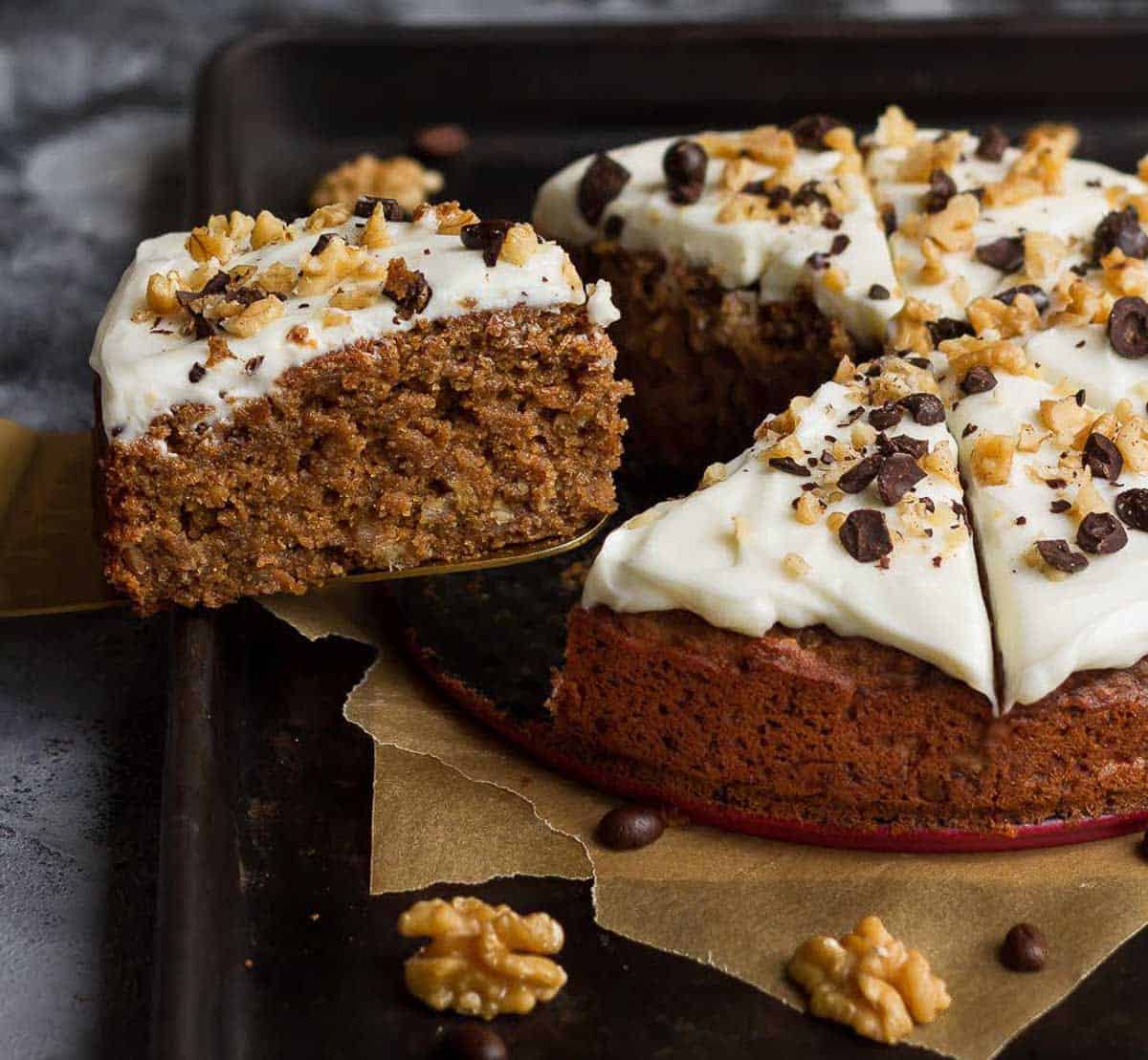 A slice of cake on a cake server being taken out of the whole cake.