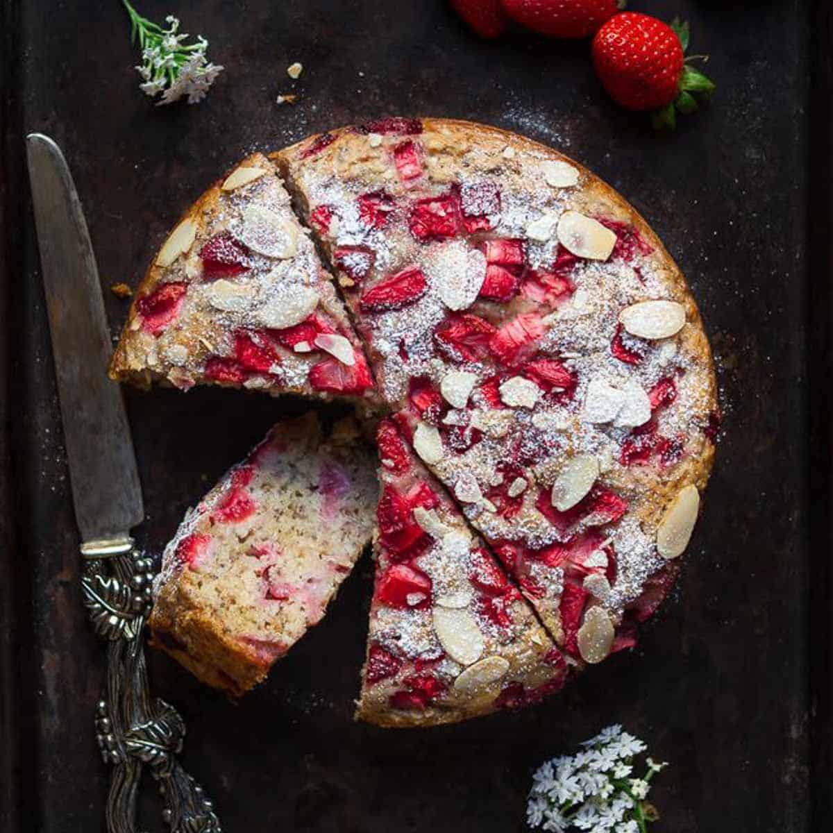 strawberry jam cake on a black tray with one slice kept down to show the texture.