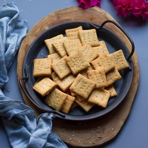 sweet mathri on a gray metal plate on a wooden board.