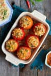 Baked stuffed tomatoes in a rectangular baking dish with ingredients around.