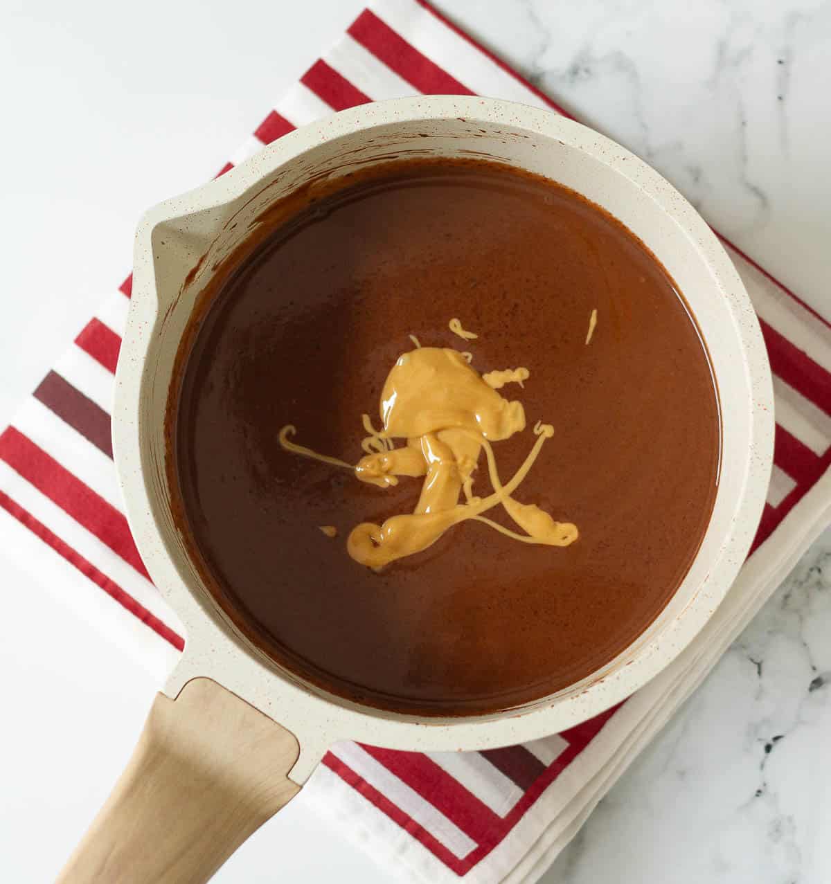 Peanut butter on top of melted chocolate in a saucepan.