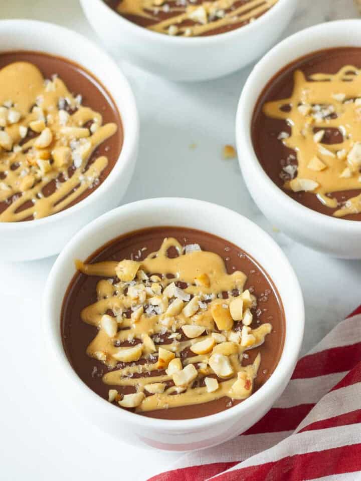 bowls of chocolate pudding with peanut butter drizzled on top.