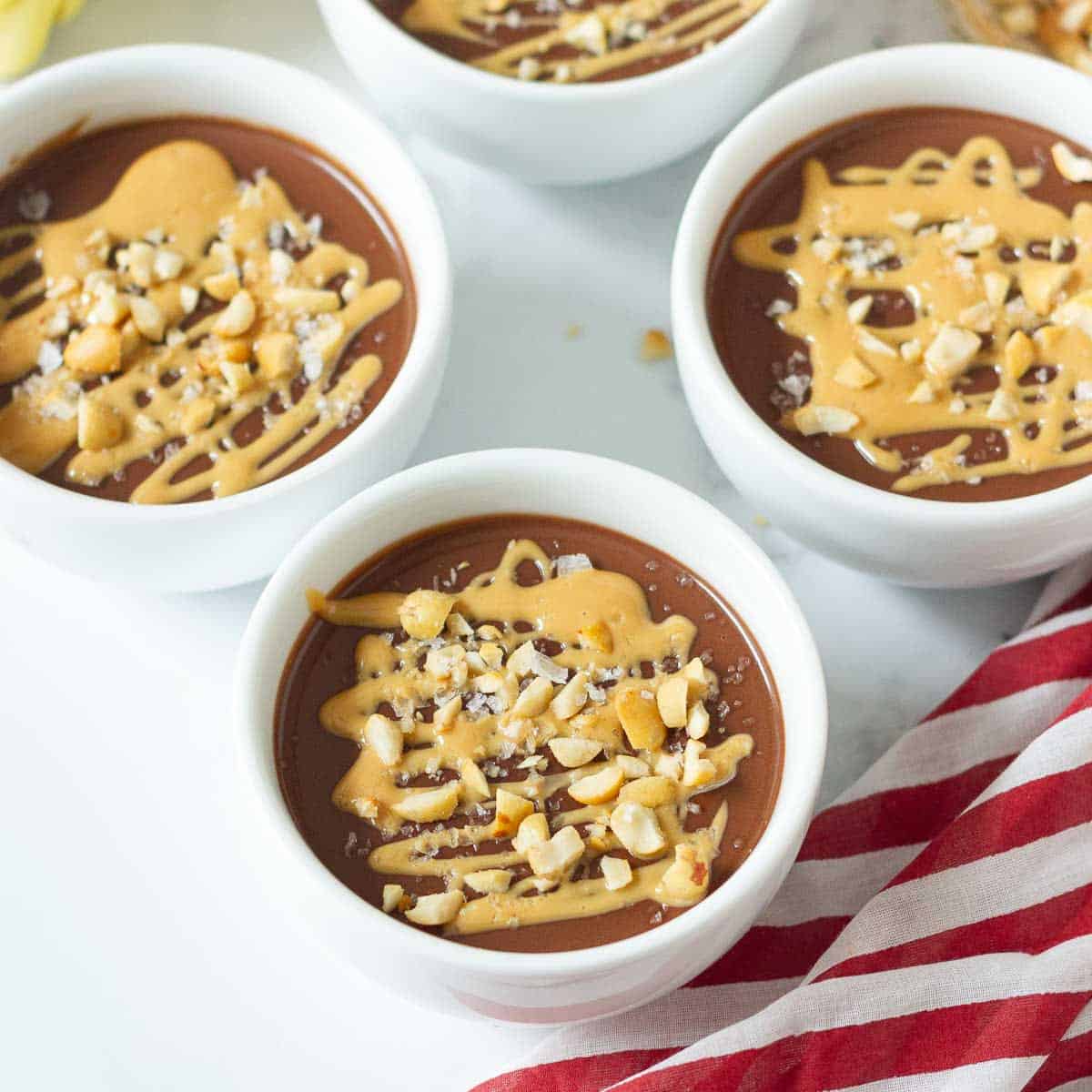 bowls of chocolate pudding with peanut butter drizzled on top.
