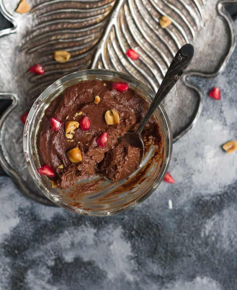 Spoon in the creamy Chocolate Peanut Butter Pudding topped with chopped peanuts and pomegranate arils