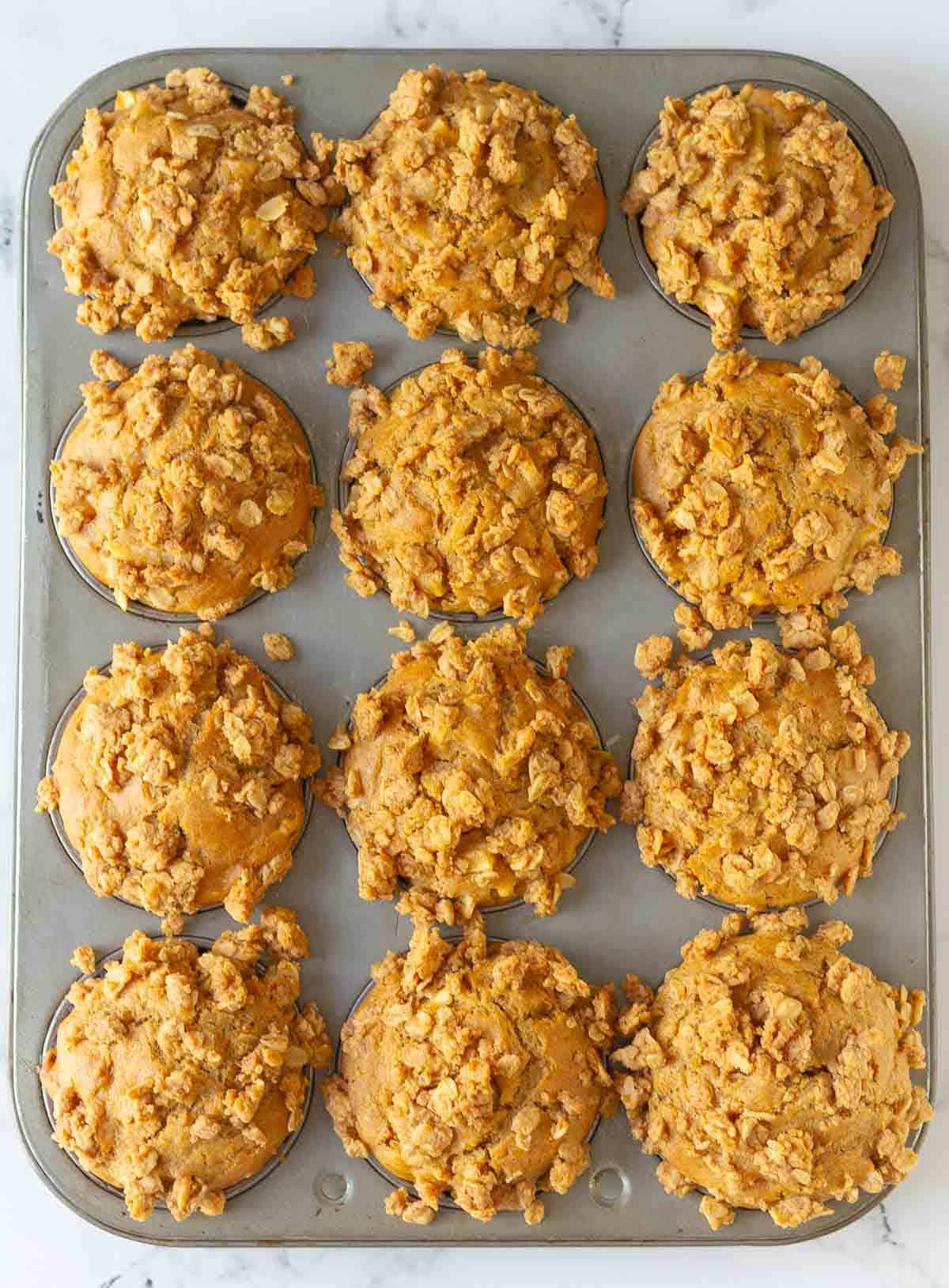 Baked apple peanut butter muffins in a muffin tray.