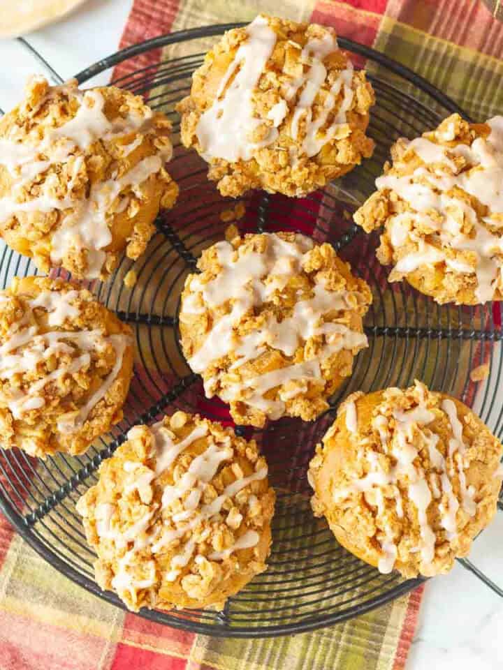 7 Peanut butter apple muffins with cinnamon glaze on a round wire rack.