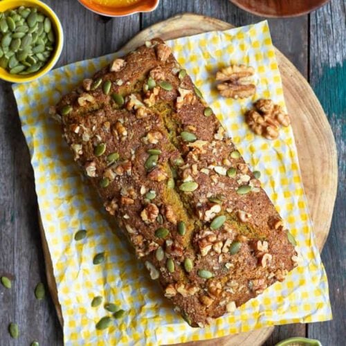 Pumpkin Bread on a wooden board with ingredients around.