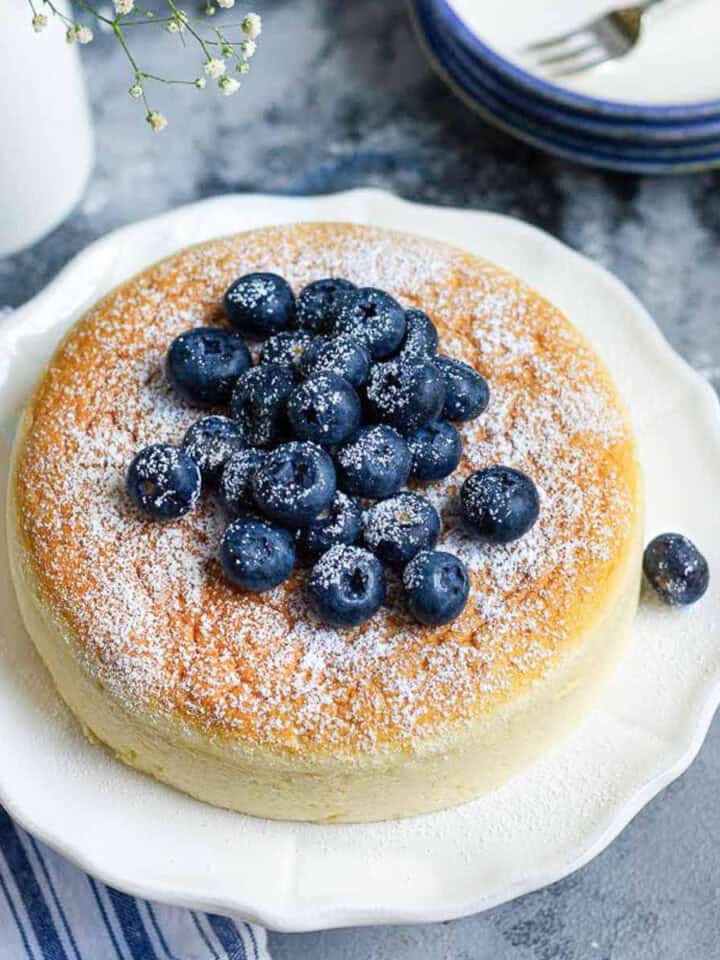 Japanese cheesecake on a white platter with blueberries on top.