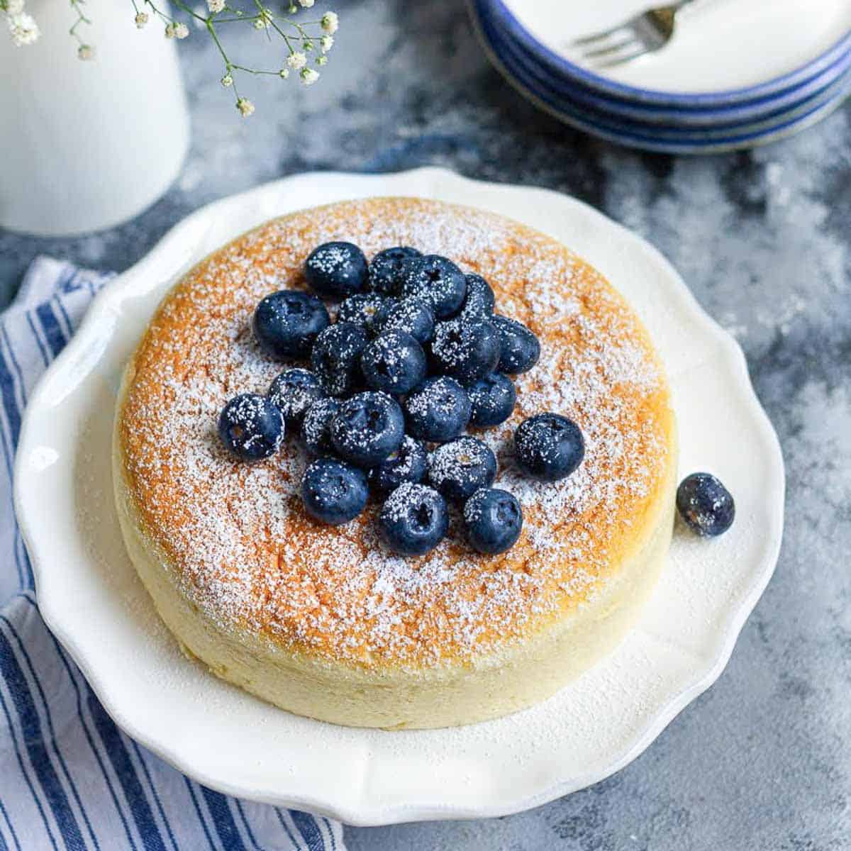 Japanese cheesecake on a white platter with blueberries on top.