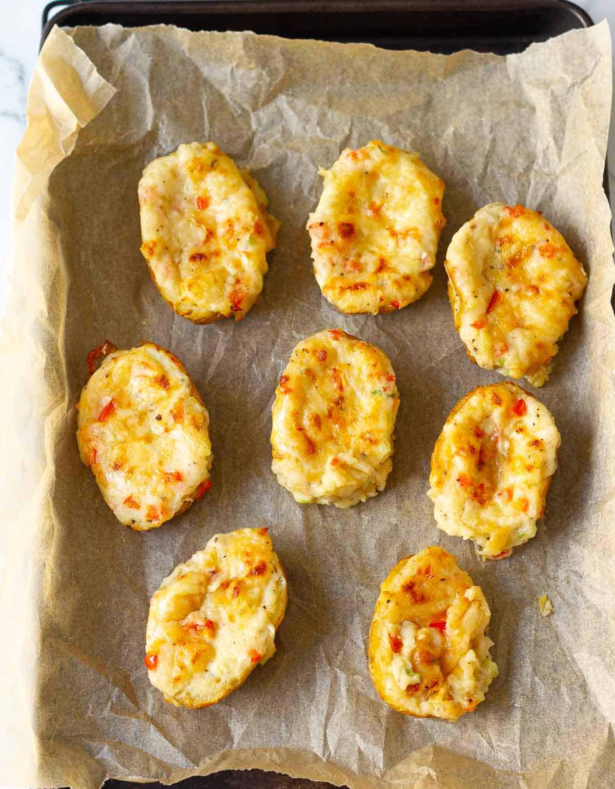 Baked loaded potatoes on a parchment-lined tray.