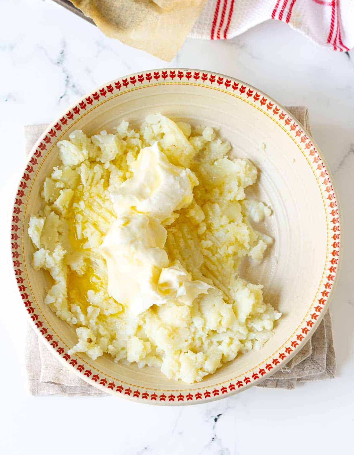 Potato flesh with cream cheese in a mixing bowl.