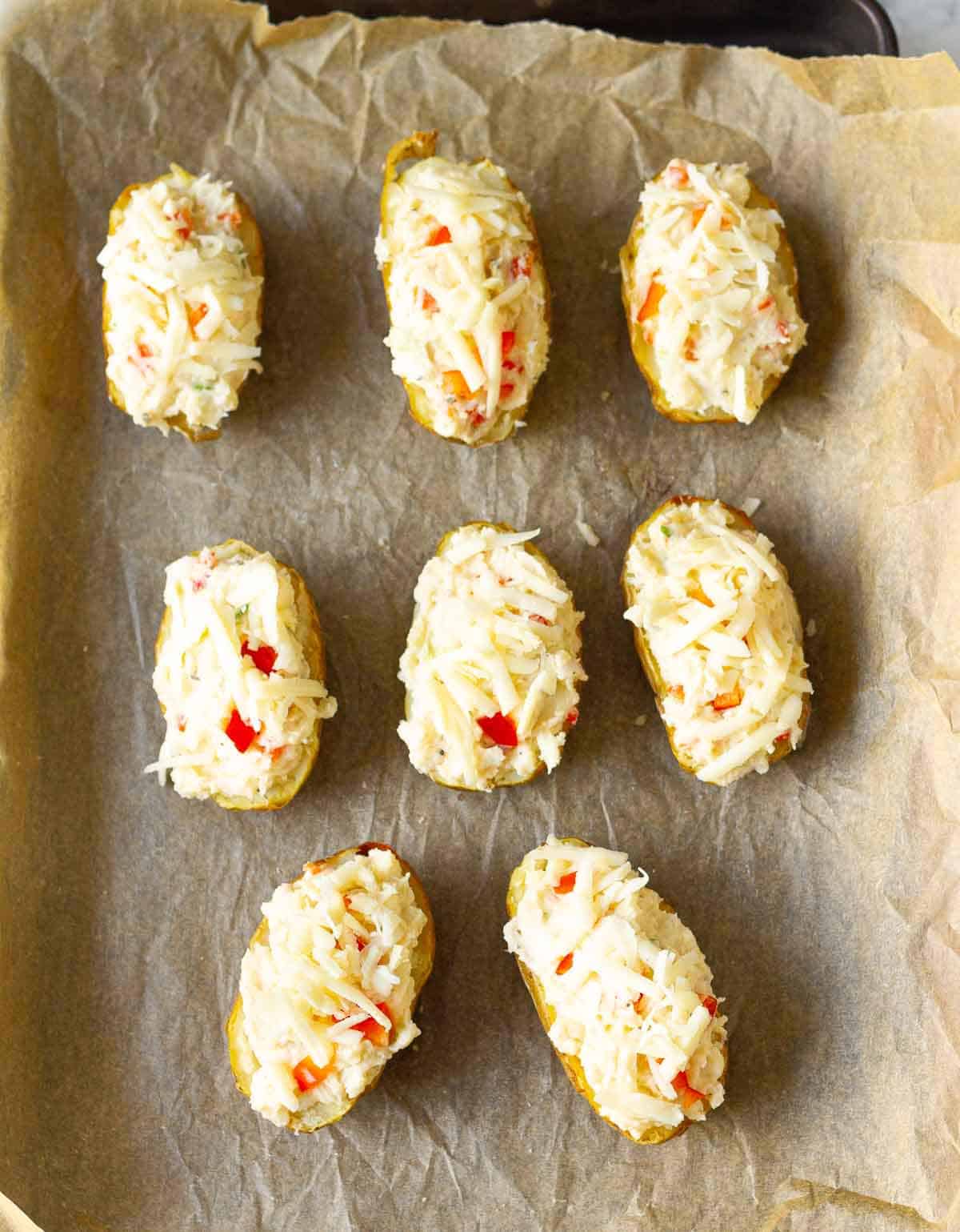 Potato skins loaded with mashed potato and cheese on a baking tray.