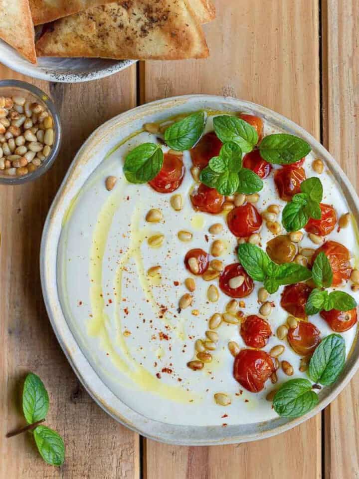 Feta dip with cherry tomatoes, pinenuts, olive oil and mint on top.
