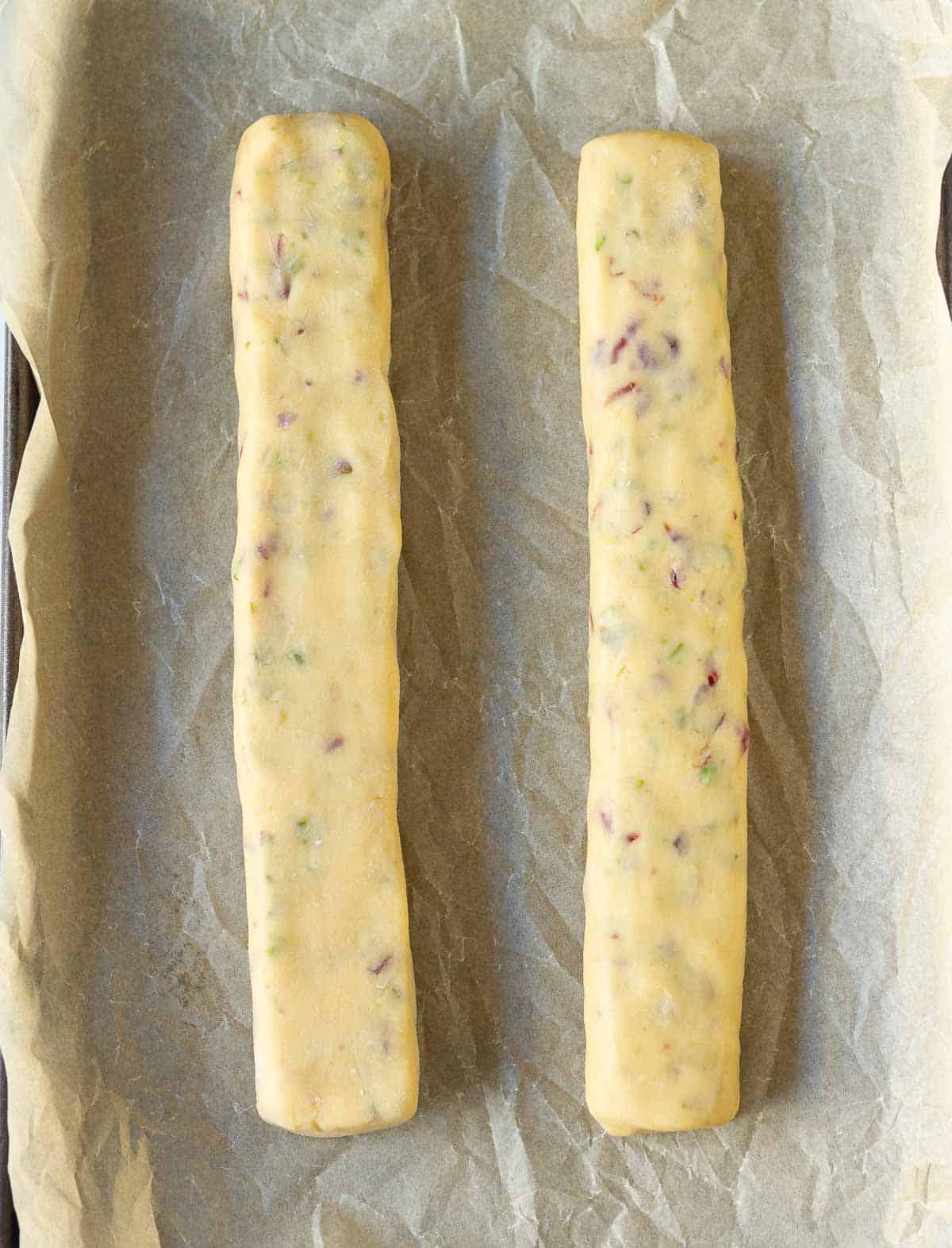 2 logs of biscotti dough on a parchment-lined baking tray.