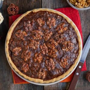 walnut pie on a red napkin with a knife alongside.