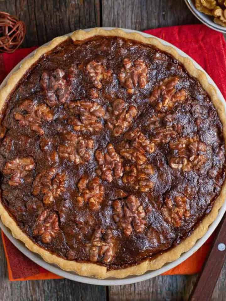 walnut pie on a red napkin with a knife alongside.