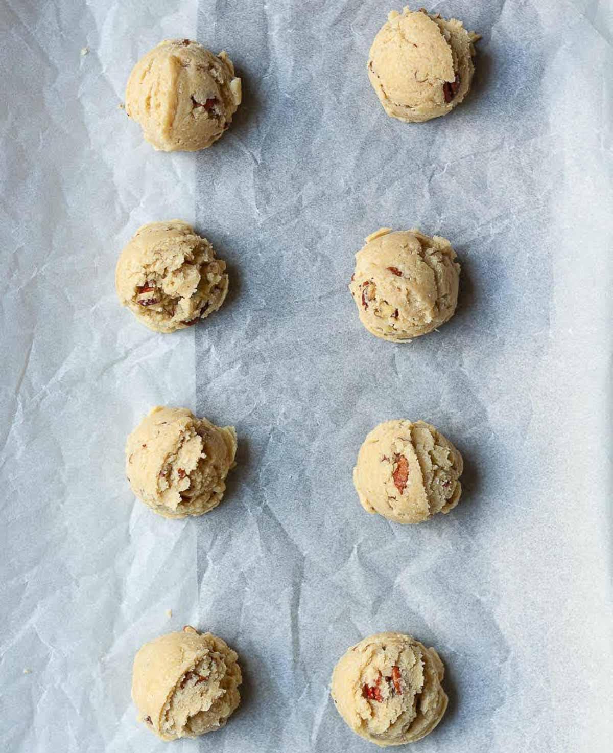 Cookie dough balls on parchment lined tray.