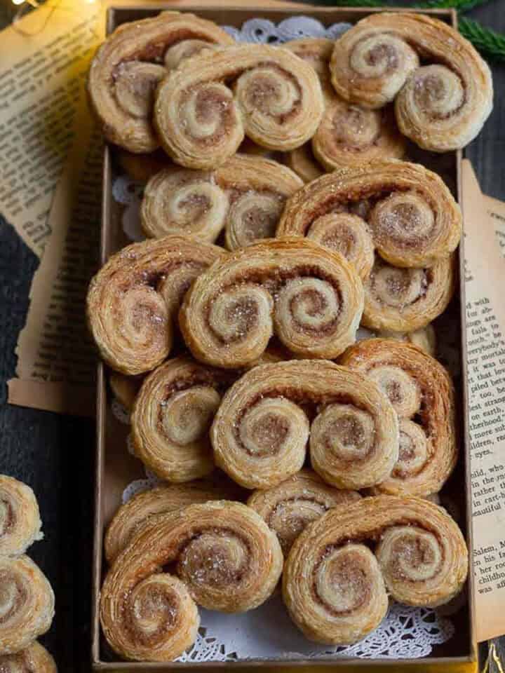 French heart cookies in a small tray on a wooden board with old papers.