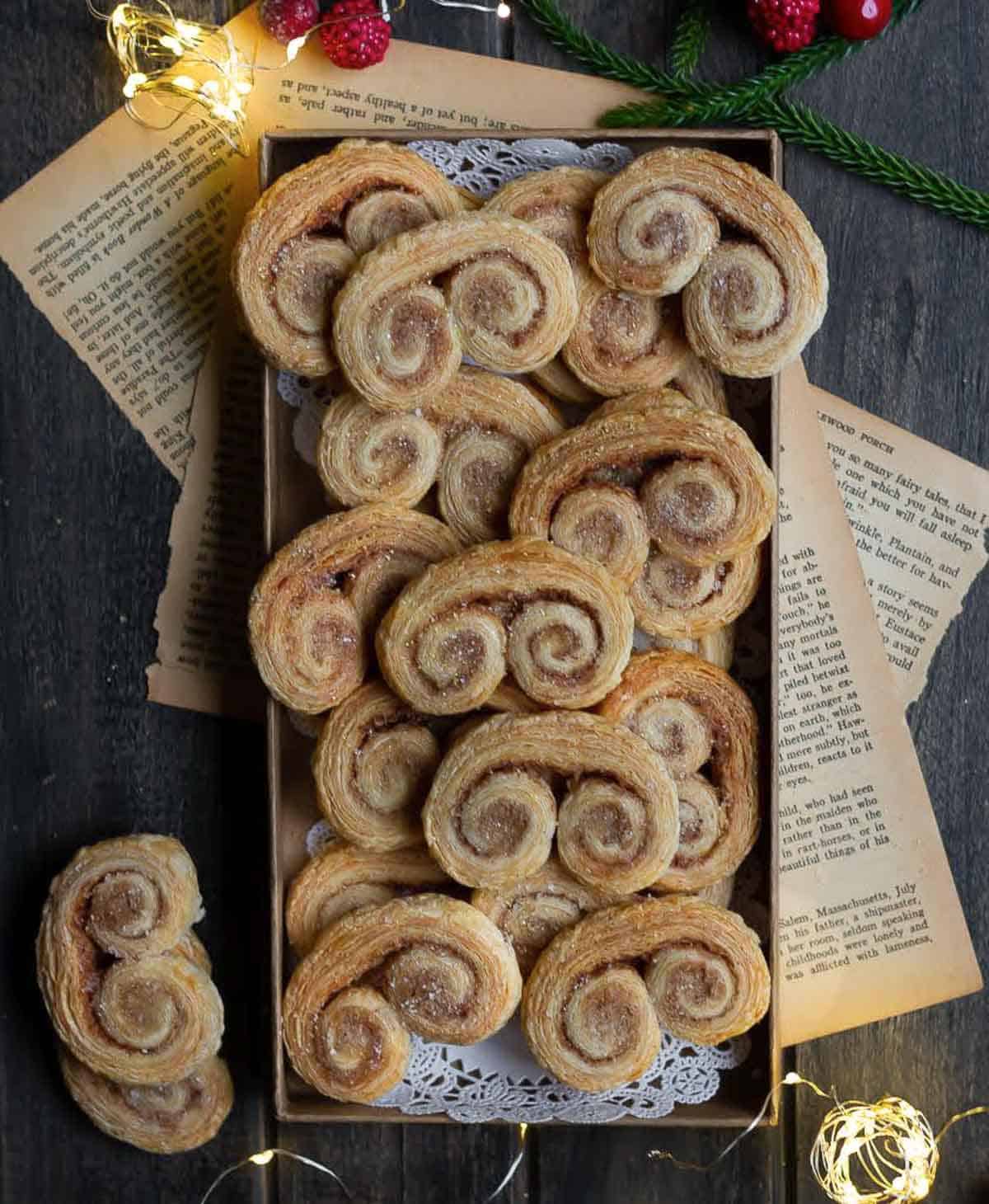 French palmiers in a small tray with lights and old papers around.