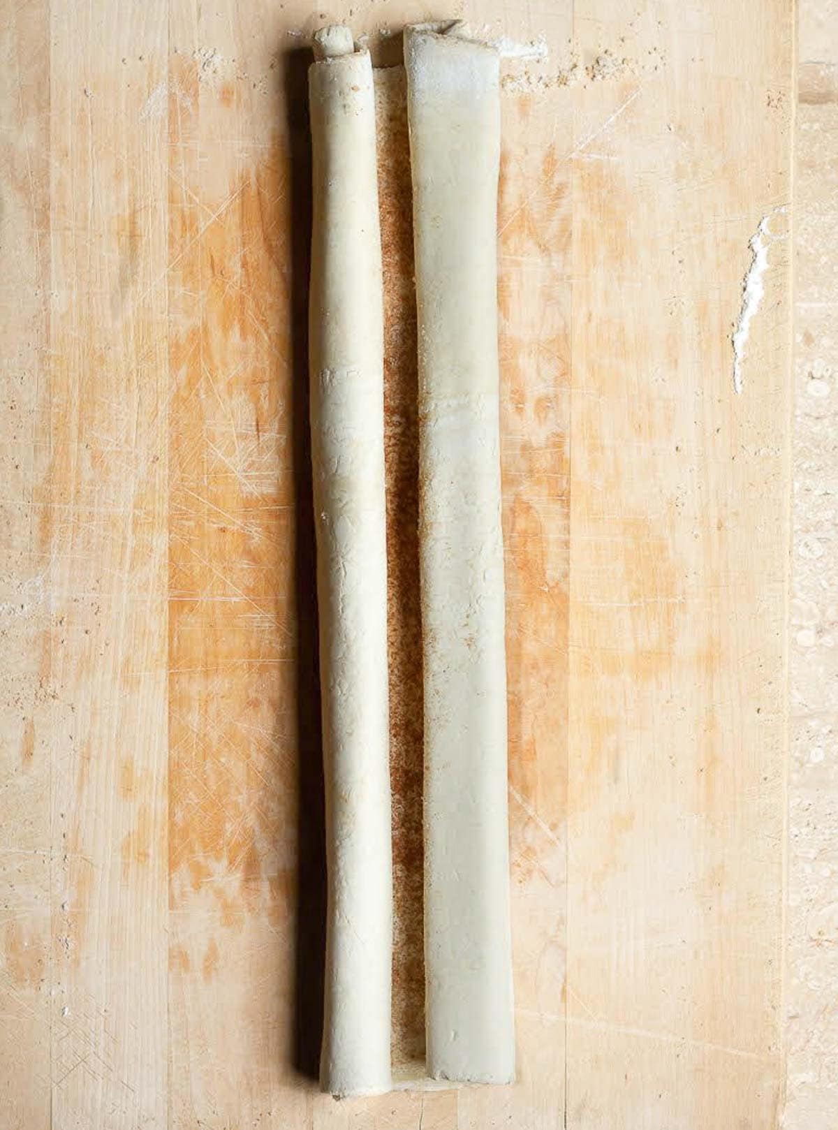 Rolled up puff pastry dough on a wooden board.