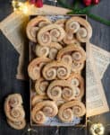 Cookies on a small tray with christmas decor and old papers around.