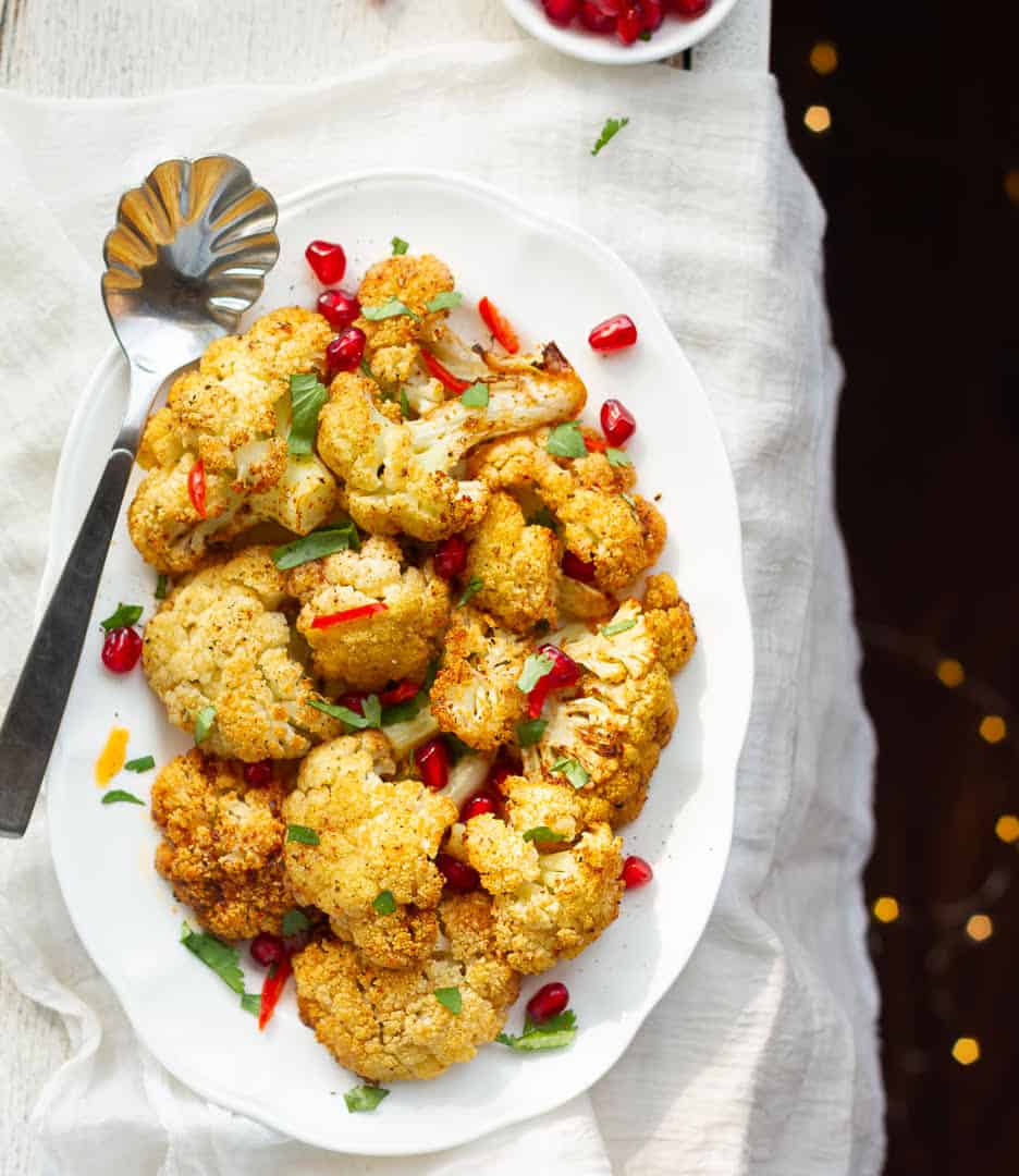 oven roasted cauliflowers on a white serving platter and silver spoon.