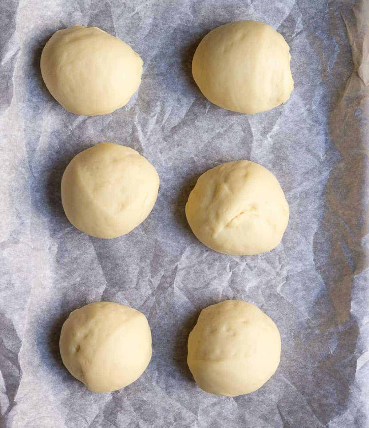 6 dough balls on parchment paper.