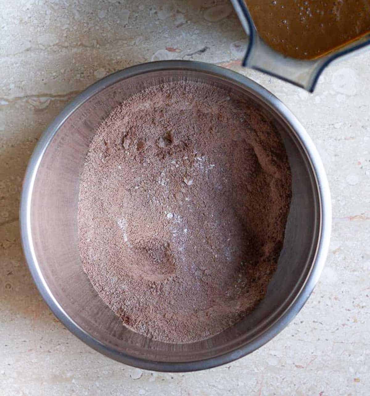 Dry ingredients in a bowl and wet ingredients in a blender for making cake.