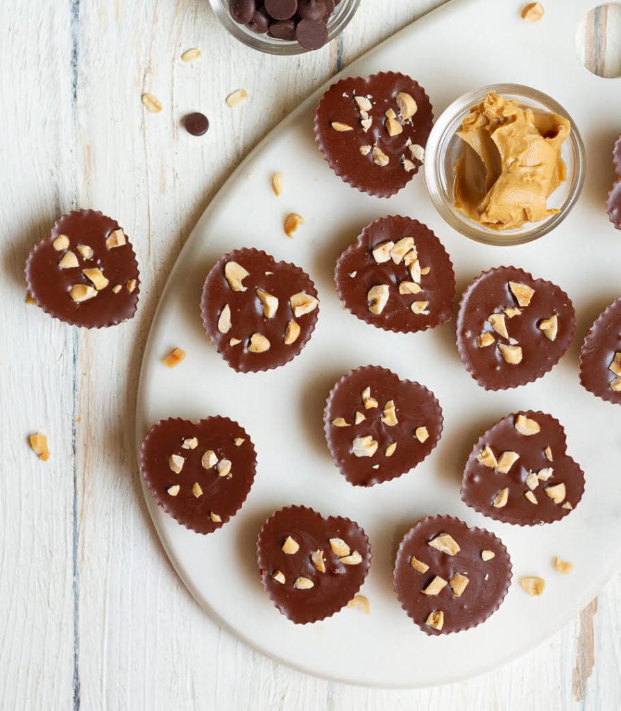 Peanut Butter Oat Cups on a white tray with peanut butter in a small bowl