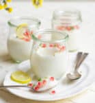 A spoonful of panna cotta on a platter with 3 jars behind it.