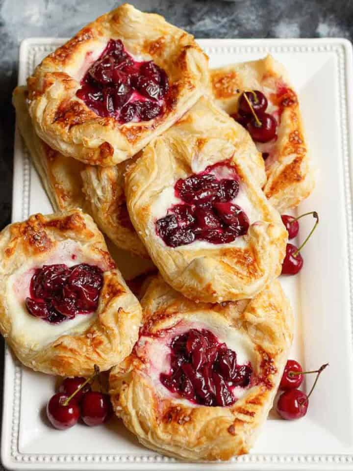 cherry puff pastry tarts on a white platter.