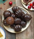 Chocolate cherry madeleines on a plate with ingredients in the background.