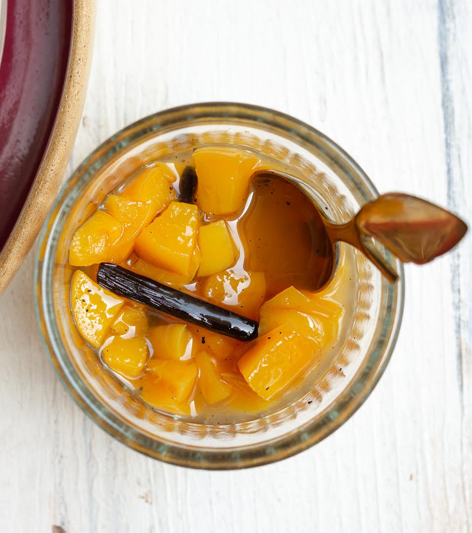 Peach compote in a small bowl with a spoon.