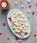 Chena murki - sugar coated paneer cubes on a plate with a candle and flowers.