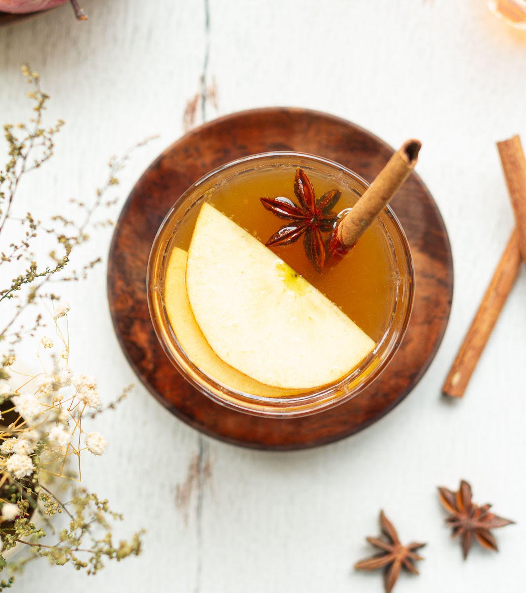 Hot toddy in a glass on a small wooden plate.