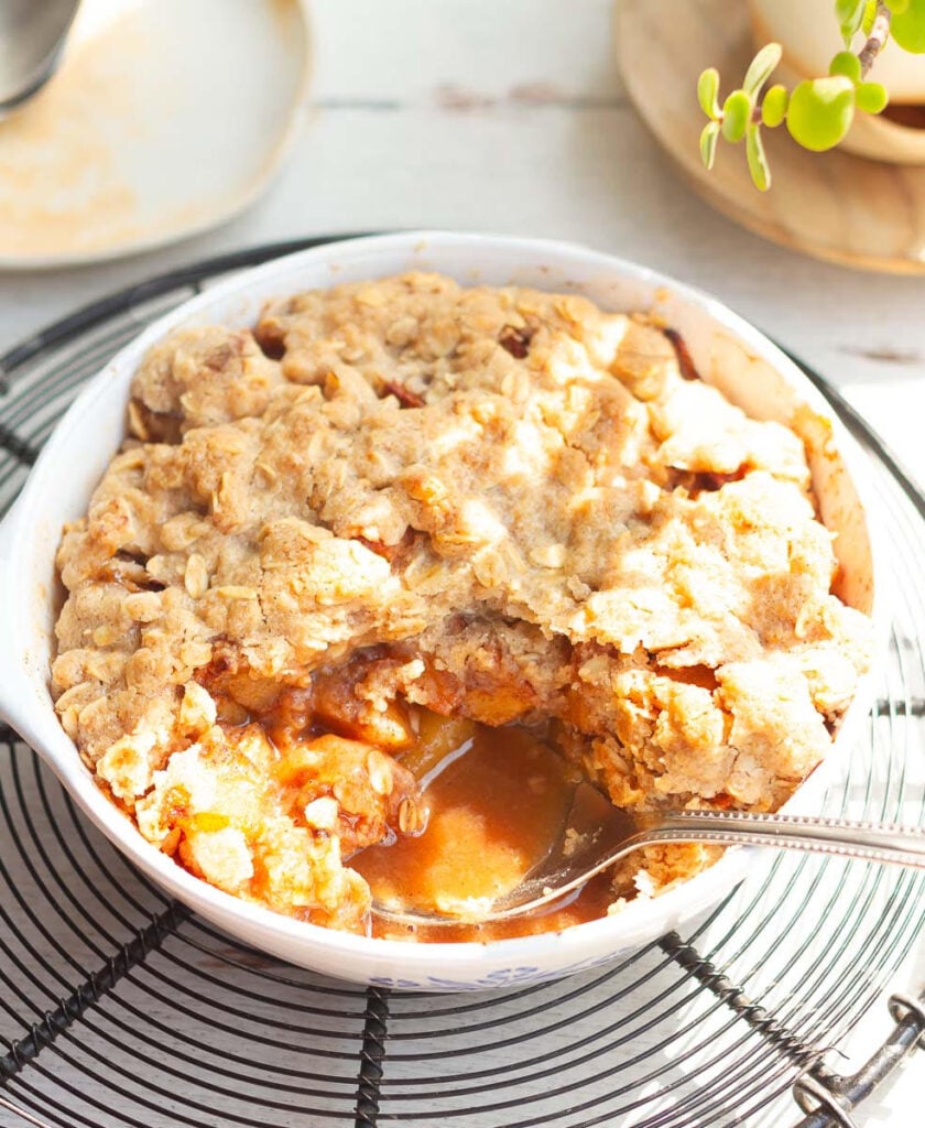 A spoon in a dish of apple crisp.